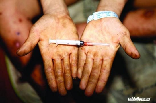 Китайский наркоман У Гуйлинь держит окровавленный шприц иглой препарат.