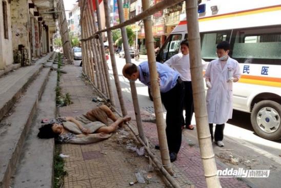 Китайский полицейский и медицинский персонал стоять рядом с наркоманом У Гуйлинь лежали на открытой улице, его тело слишком слаб, чтобы ходить.